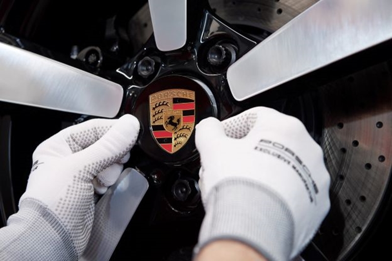 Two hands putting the Porsche logo on a wheel